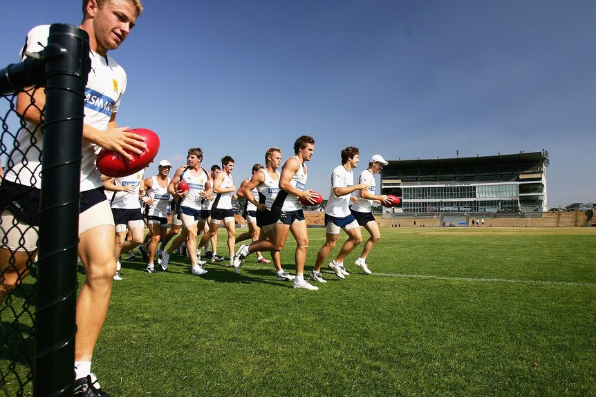 Hawthorn Footballers run laps on the Waverley Park oval with the stand in the background