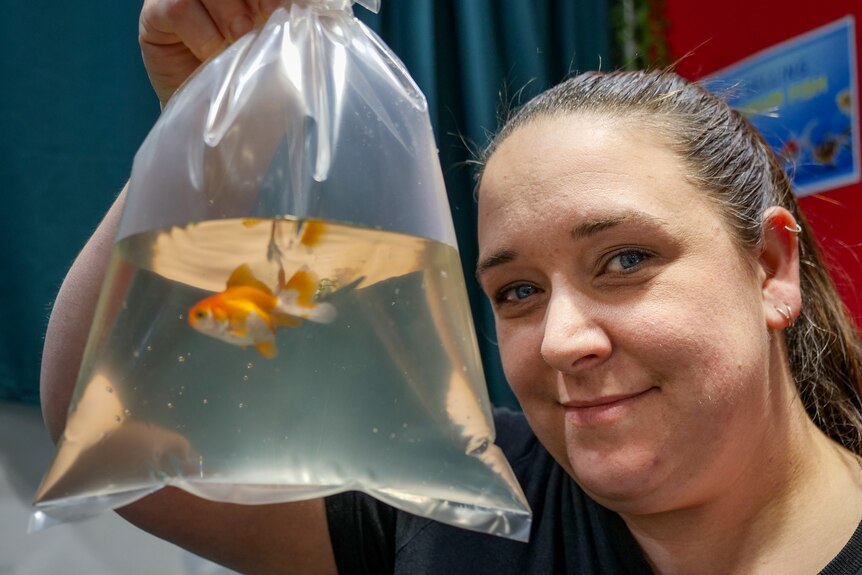Tegan looks at the camera with a goldfish in a bag