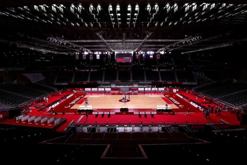 A view from the stands of a wheelchair rugby court, including the goal area marked as red rectangles at either end.
