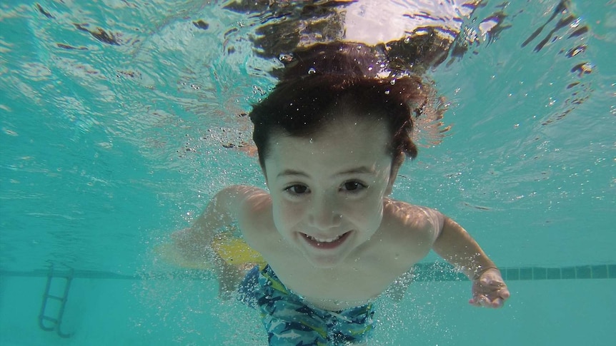 A boy in a swimming pool, viewed from under water.