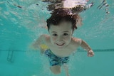 A boy in a swimming pool, viewed from under water.