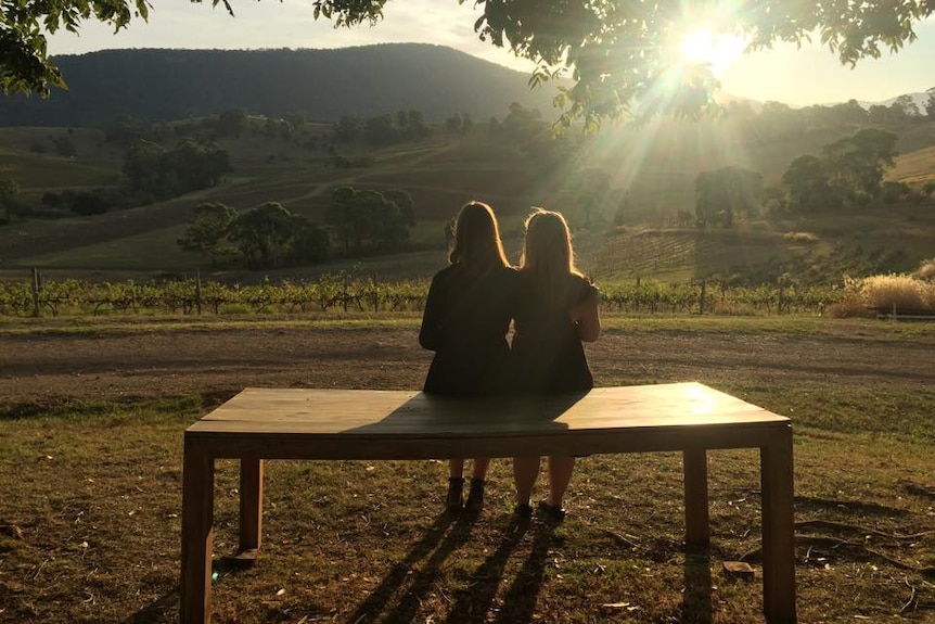 Two women enjoy a sunset view in a winery.