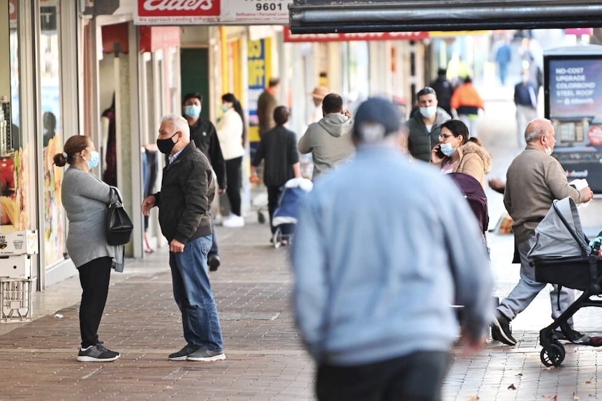 People wearing masks walk along a street