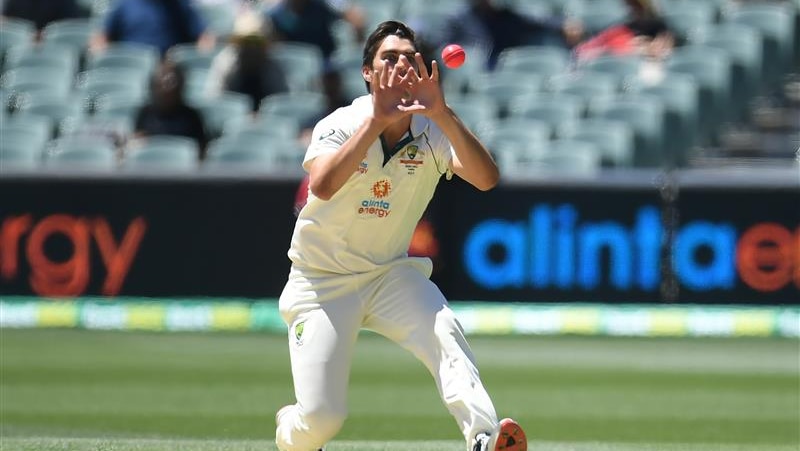 Cummins watches the ball as it's about to land in his hands.