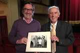 Greg Hocking, John Cain pose with a photo of comedy festival participants