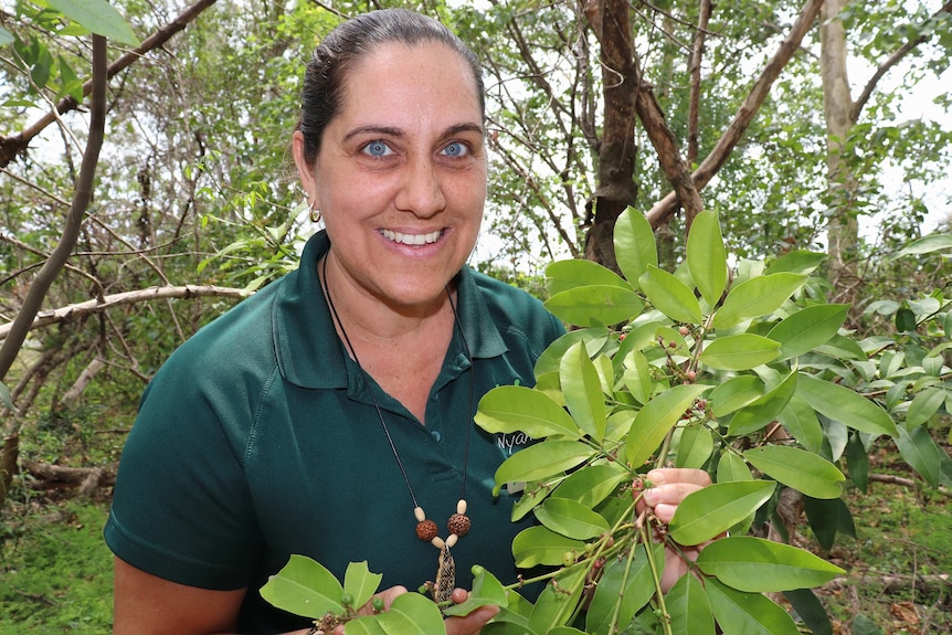 Tour guide Madonna Thomson holds a branch with pink native lime berries on it.