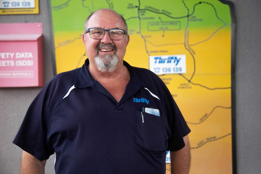 Steve Shearer stands in front of a Northern Territory map at his Alice Springs car hire business.