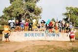 AFL mascots pose on top of a stone wall that bears the name "Bordertown".