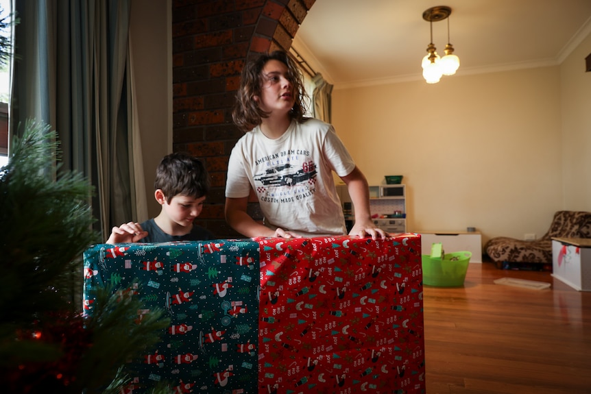 Kate's two sons look at Christmas presents under the tree