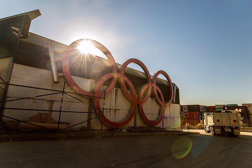 Colour photograph of red Sydney Olympic rings affixed to the side of a large warehouse.