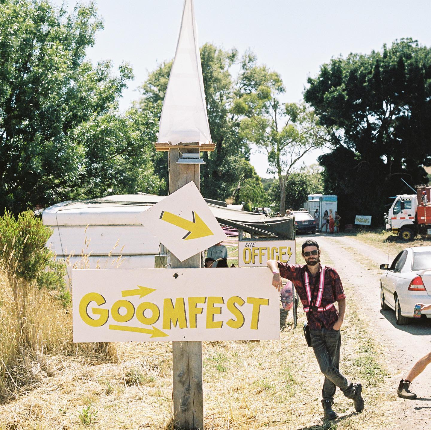 A man stands next to a goomfest sign