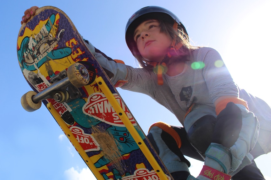 Girl holding skateboard.