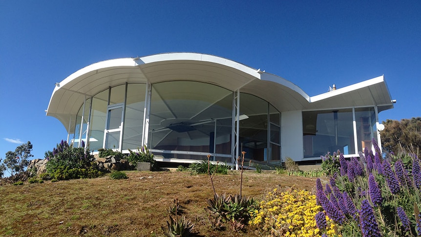 the front of a modern designed house, it is circular with lots of glass