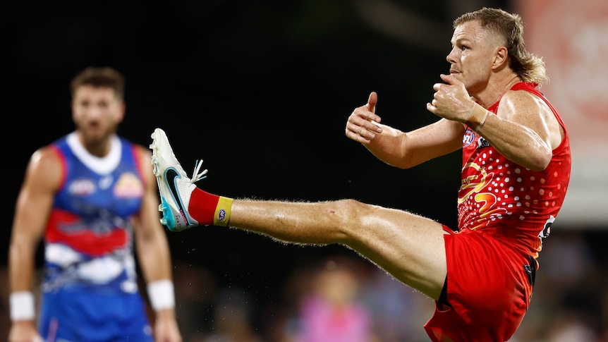 A Gold Coast Suns AFL player kicks for goal with his left foot against the Western Bulldogs.