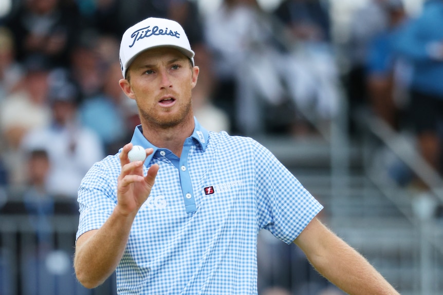American golfer Will Zalatoris holds a golf ball in his hand as he waves to the crowd at the US Open.