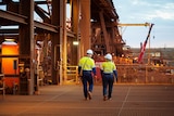 Two workers at Fortescue Metals Group's Cloudbreak mine walking on the site