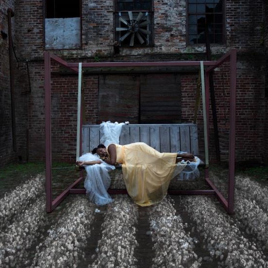 A photo of a woman asleep on an outdoor chair over raked piles of pebbles