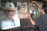 Thai metal worker hangs up portraits of the royal family.