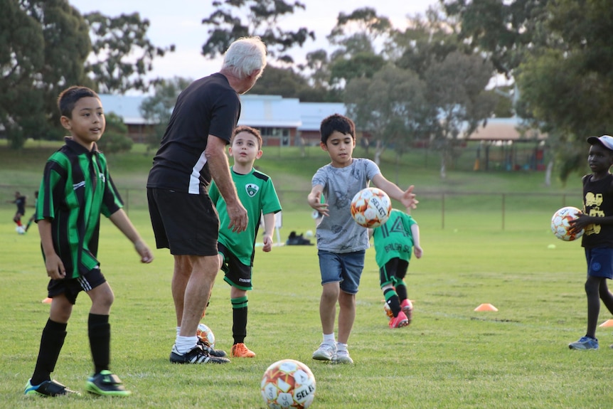 Ken Shorto on the field with players kicking the ball.