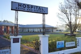 A sign reading 'Keith and District Hospital' stands in front of a grassy lawn and long brick building.