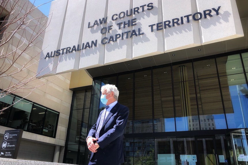 A lawyer leaves court wearing a mask and suit