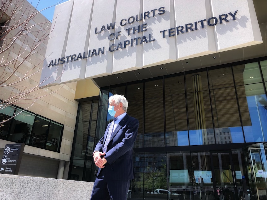 A lawyer leaves court wearing a mask and suit