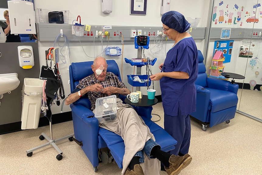 Patient Allen Ford, 73, sits in an armchair in a recovery hospital room after eye cataract surgery