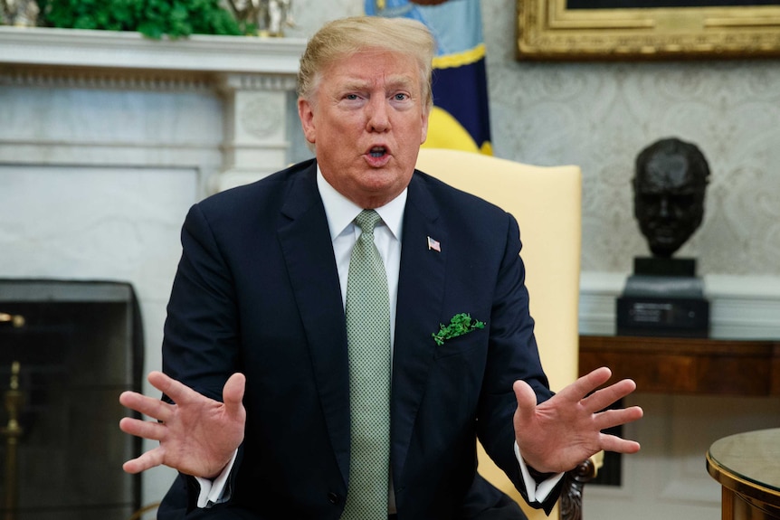 US President Donald Trump gestures while talking in the Oval Office.