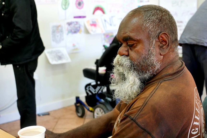 A man looking down while he drinks his coffee.