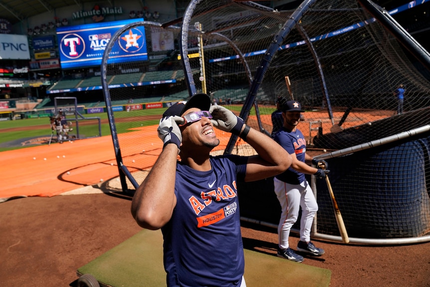 Dixon Machado looks up at the sun wearing eclipse glasses and his Houston Astros' uniform