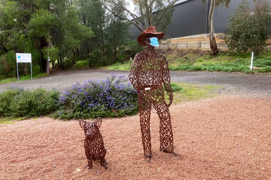 A statue wearing a face mask standing next to a statue of a pig