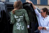 The back of Melania Trump's jacket is visible as she gets into a vehicle.