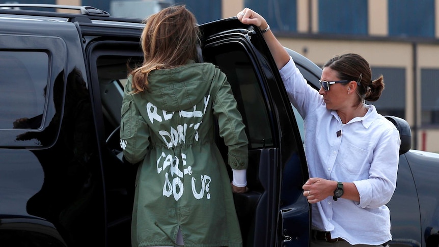 The back of Melania Trump's jacket is visible as she gets into a vehicle.