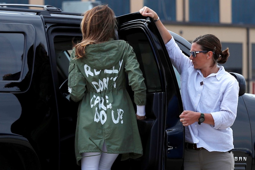 The back of Melania Trump's jacket is visible as she gets into a vehicle.