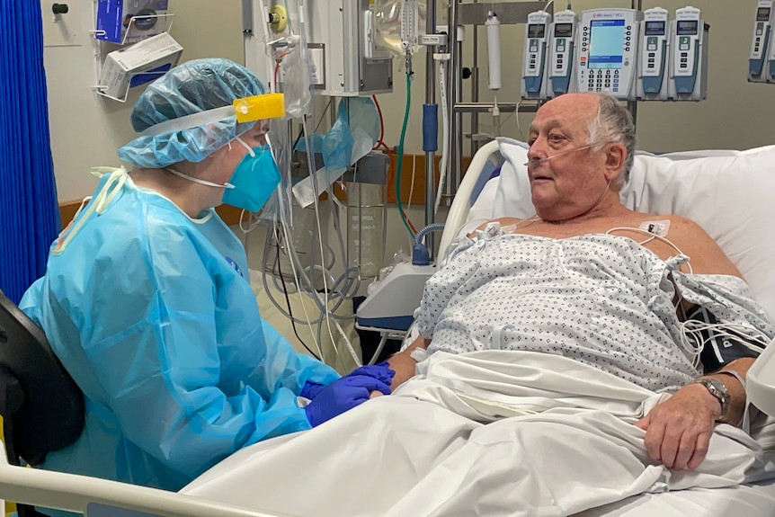 Nurse sitting next to a COVID patient in bed. 