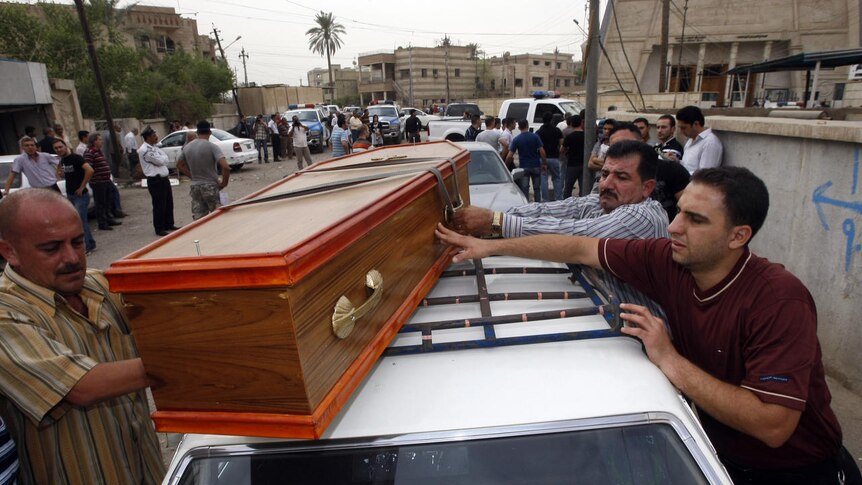 Iraqi men load a victim's coffin onto a car outside the Sayidat al-Nejat Catholic Cathedral