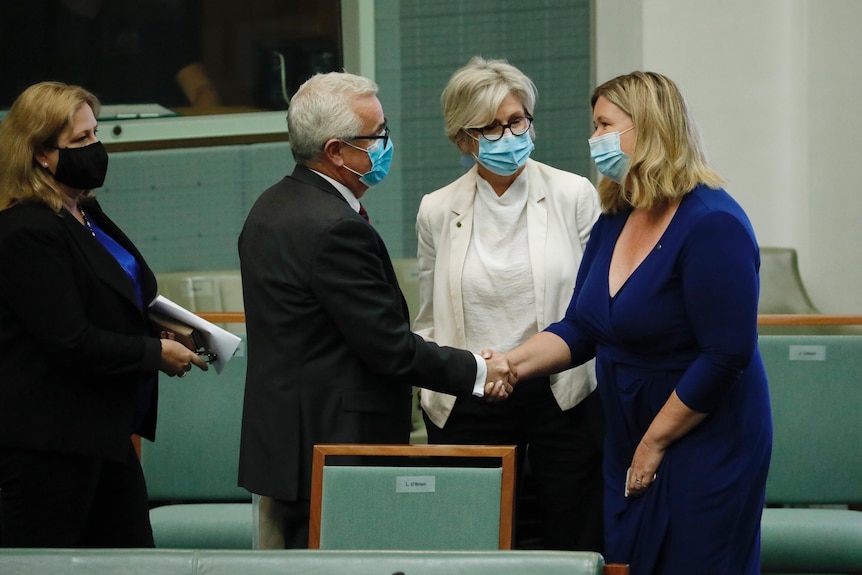 A group of people chat and shake hands on the floor of the House of Representatives.