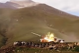 A still image of a missile being shot from a tank with mountains in the background.