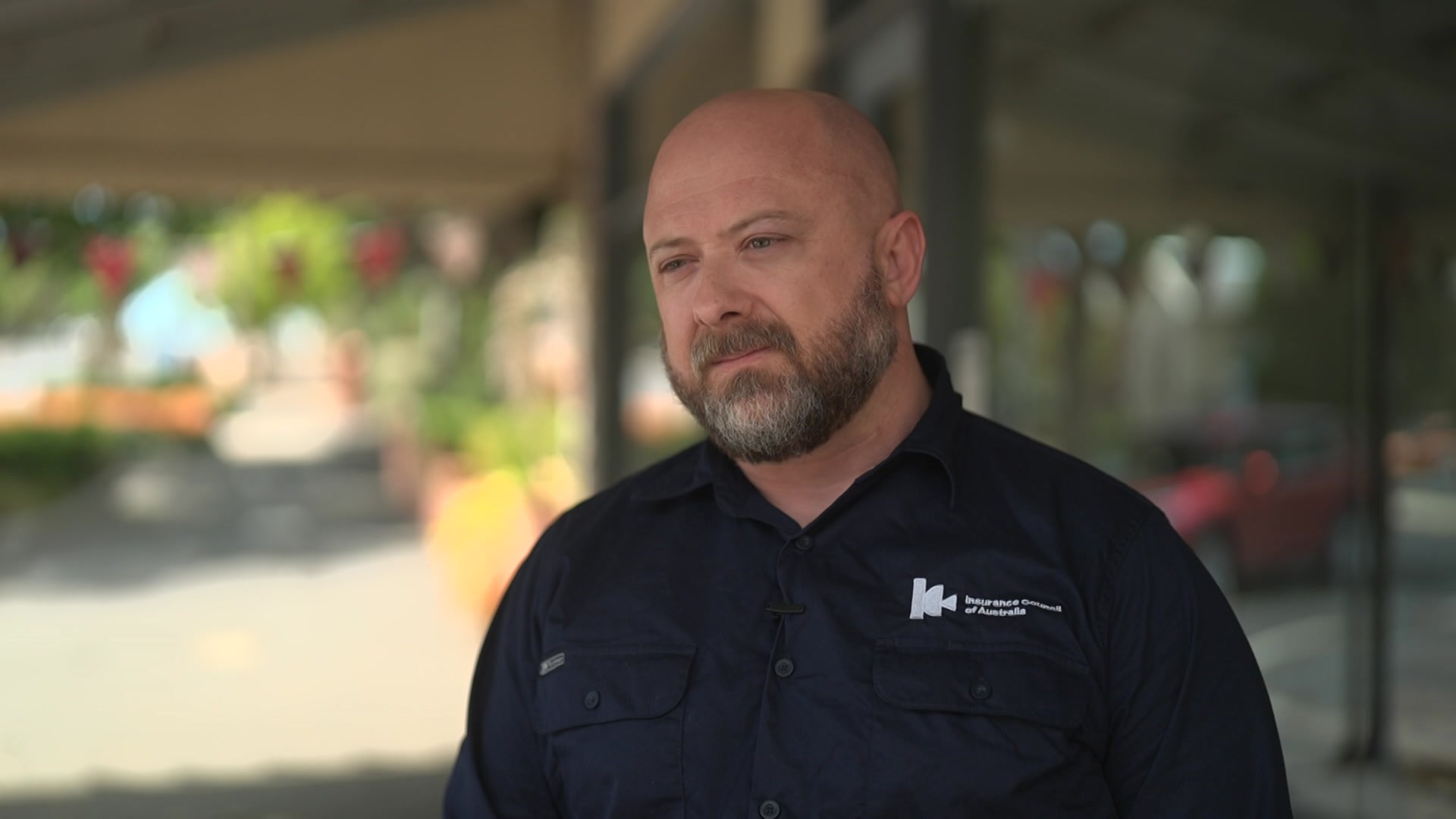 Um homem de camisa pólo preta olha para fora da câmera. 