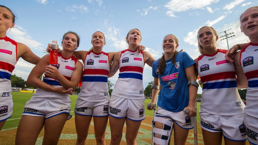Western Bulldogs AFLW player Isabel Huntington (in a brace) joins teammates in celebration.