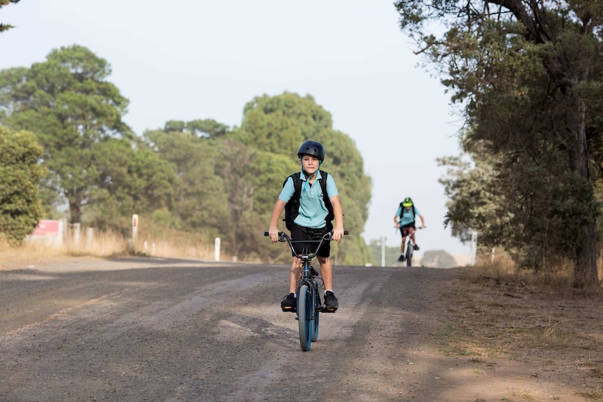 Diesel Ferraro, followed by his older brother Dylan, bikes along the section of dirt road.