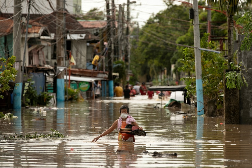 Residents wade through waist-deep flood waters after Super Typhoon Noru.