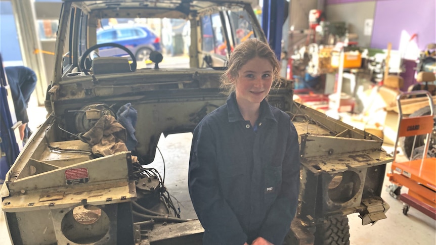 teenage girl standing in front of a stripped back Range Rover car. 