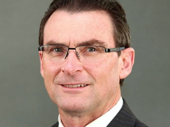 Profile photo of a man with dark hair and glasses, wearing a suit and smiling.