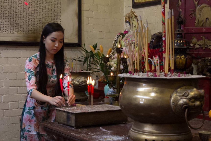 Kimmy Dao placing candles on the alter in a buddhist temple