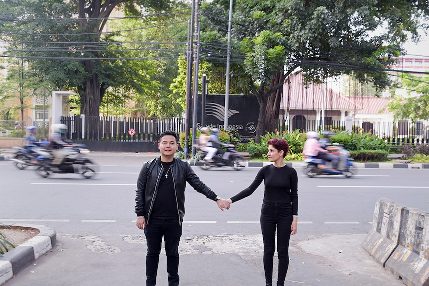 A couple holds hands on a busy street