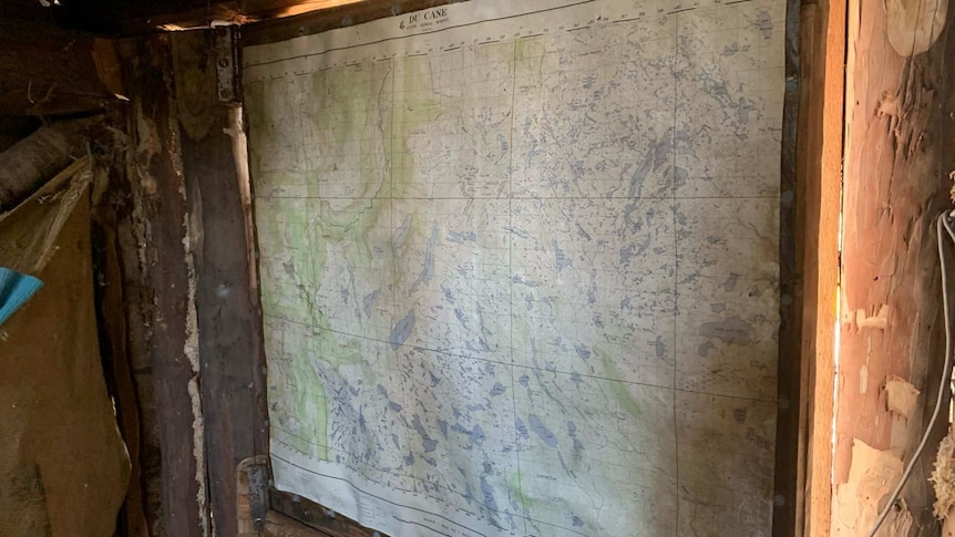 An old, water-damaged map stuck up on a wall inside a wooden hut