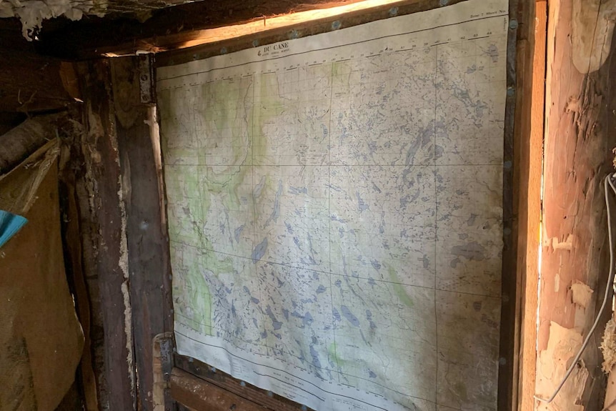 An old, water-damaged map stuck up on a wall inside a wooden hut