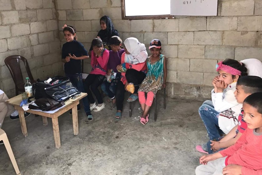 Children wait in a makeshift medical clinic in a refugee camp in Lebanon.