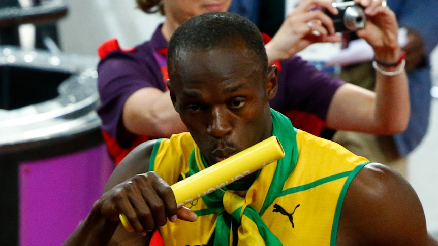Usain Bolt kisses the baton after Jamaica wins the 4x100m relay final at the London Olympics.